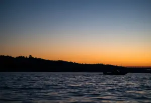 Serene view of South Holston Lake with a silhouette of a boat near a bridge