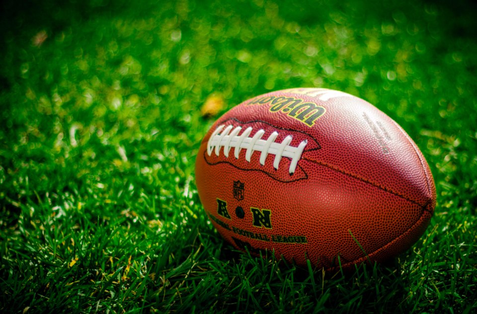 American football resting on grass field
